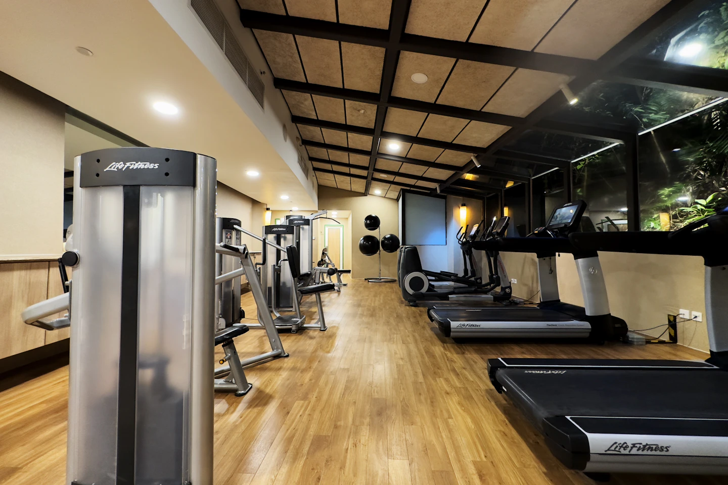 A warm, modern hotel gym with treadmills and strength equipment